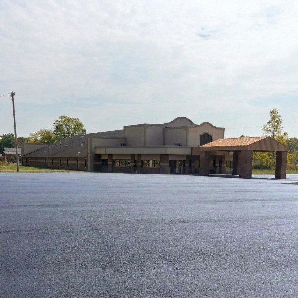 Freshly paved large commercial parking lot in front of a retail building with covered entrance