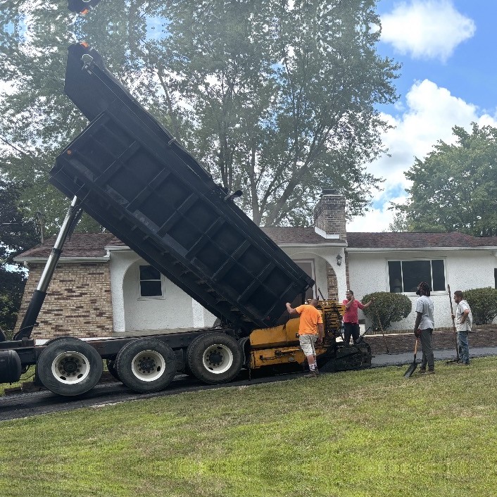 Paving crew with raised dump truck and asphalt paver on a residential driveway job in Northeast Ohio