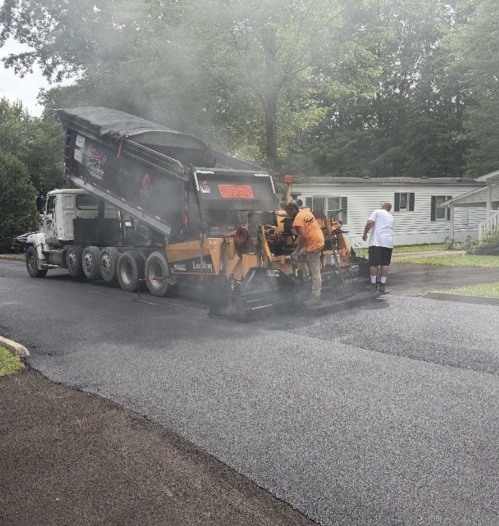Dump truck feeding LeeBoy asphalt paver on a residential driveway paving project